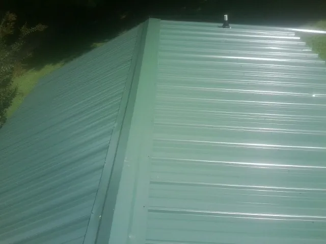 New green metal panels meeting at the ridge of a roof — Flat Roof Repair work by our crew in Cobbtown