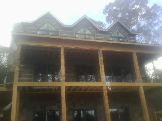 Dormers and porch framing on a large log home under construction — Roof Coating work by our crew in Cobbtown