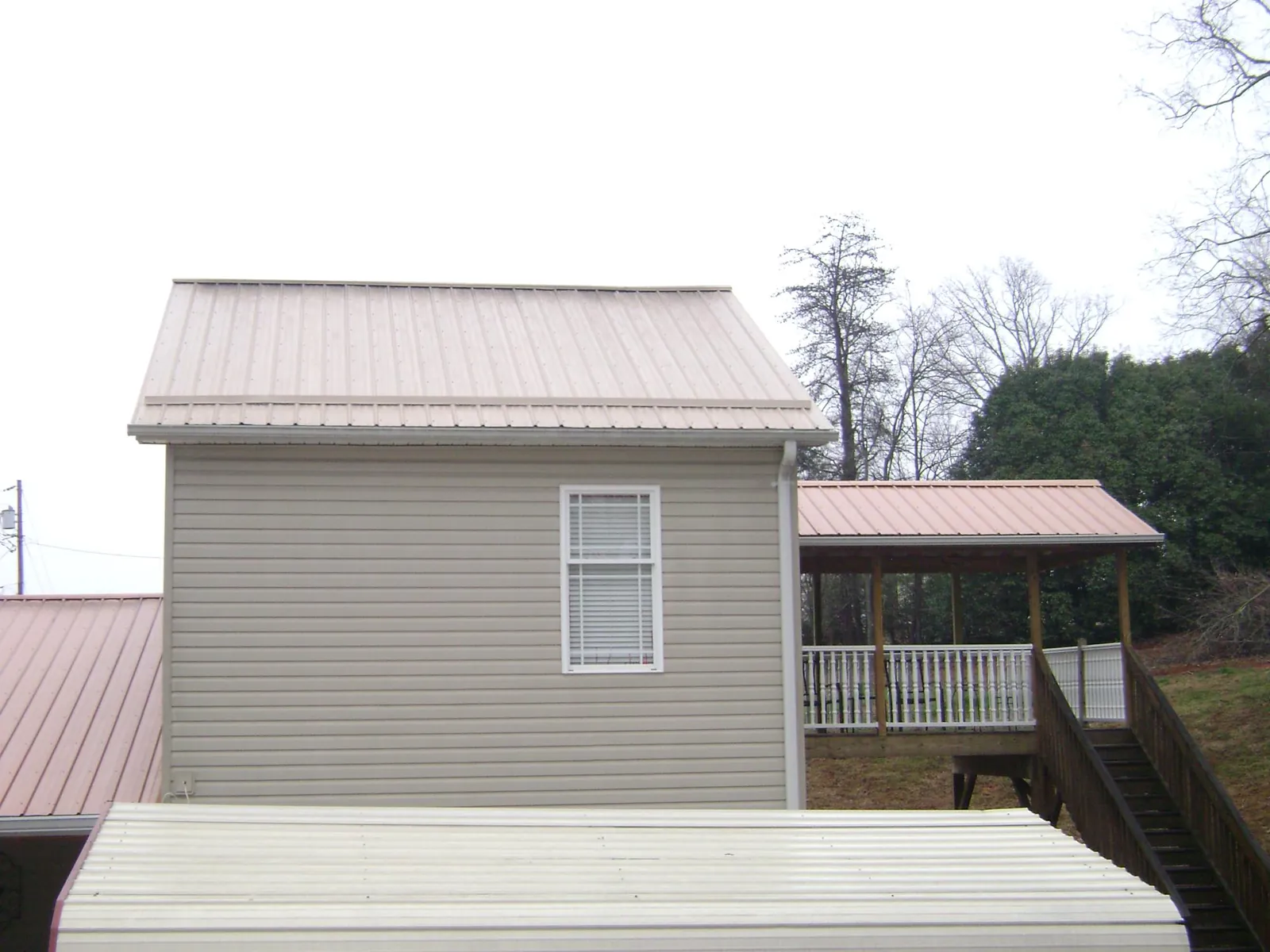 Tan metal roofs on a two story addition and attached porch, from a Roof Replacement job in Cobbtown