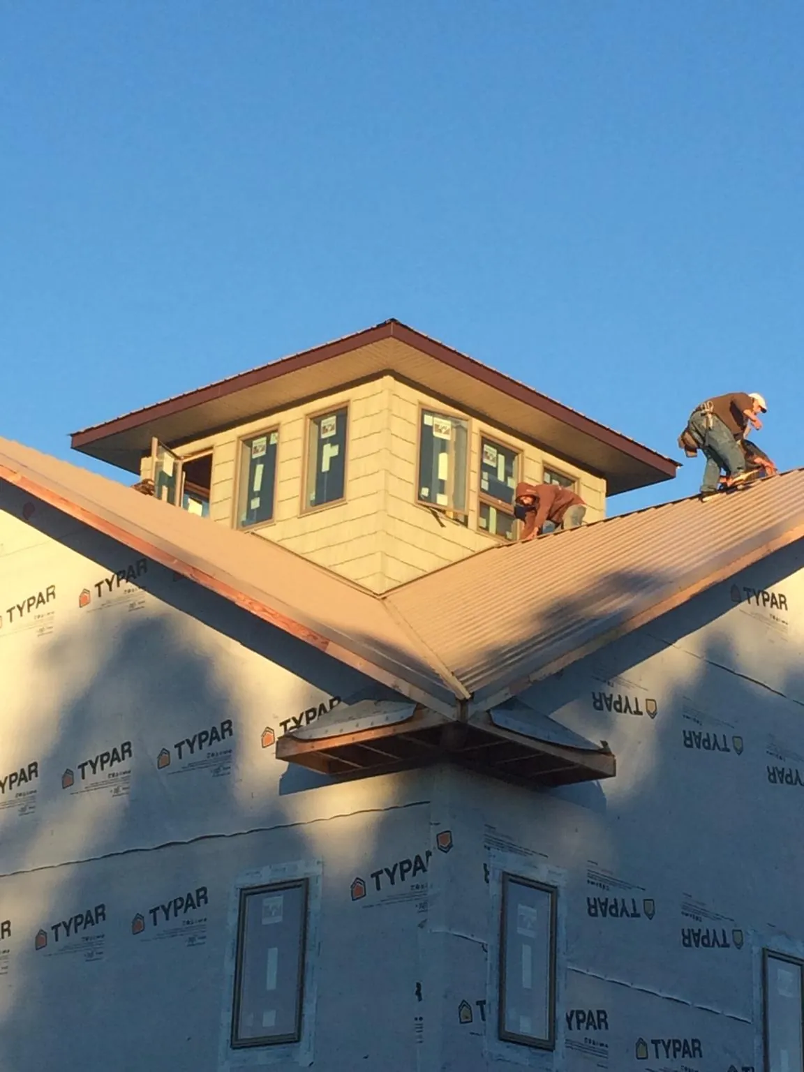 Roofers working around a rooftop cupola on a new metal roof at sunset — Roof Waterproofing in Cobbtown by Roofing Brothers